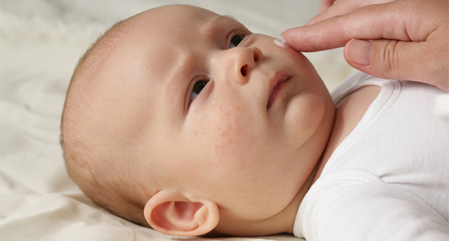 Female hand applying the cream on baby's face