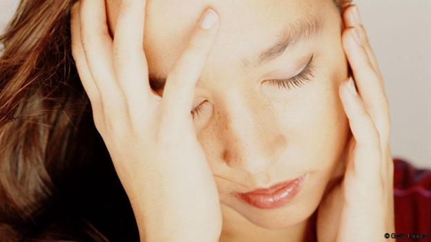 Young woman with eyes closed, head in hands, close-up