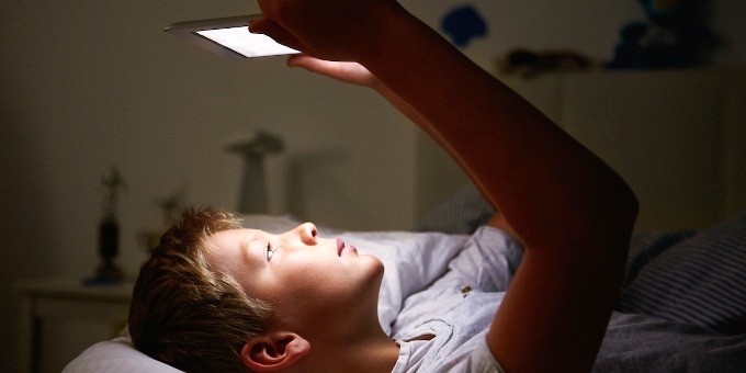 Boy Looking At Digital Tablet In Bed At Night