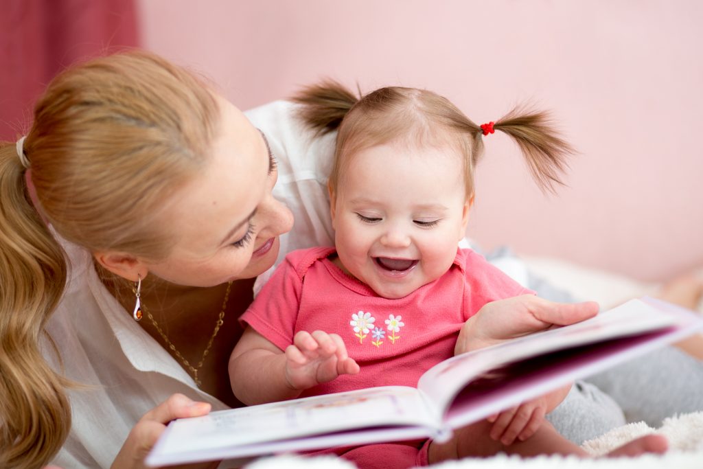 happy mother read a book to child girl indoors