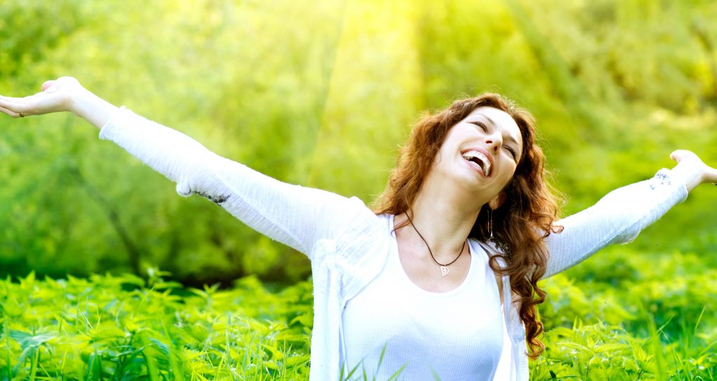 Beautiful Young Woman Outdoors. Enjoy Nature. Healthy Smiling Girl in Green Grass.